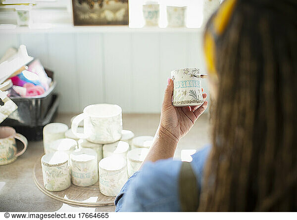 Young female artist painting ceramic mug in art studio