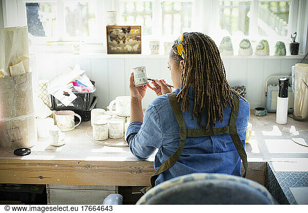 Young female artist painting ceramics in art studio