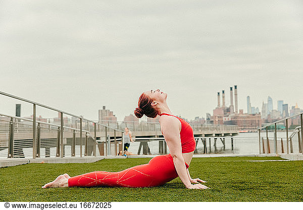 Young female athlete stretching by waterfront in Brooklyn.