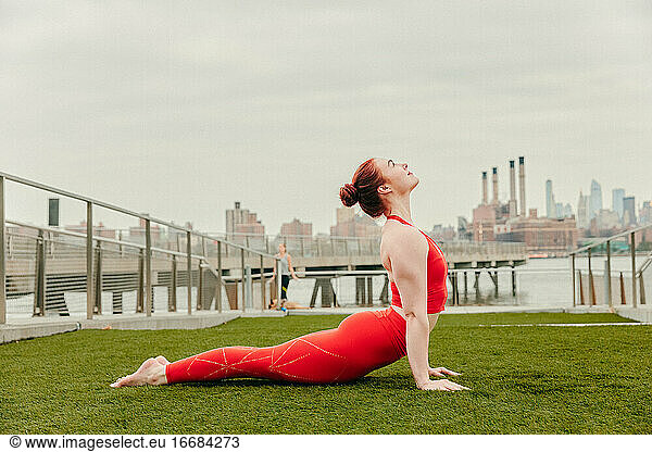 Young female athlete stretching by waterfront in Brooklyn.