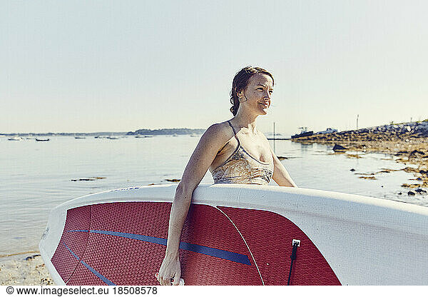 Young female carrying a standup paddle board in Casco Bay  Maine
