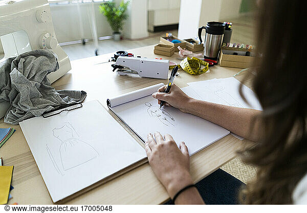 Young female creative designer sketching design in book at studio