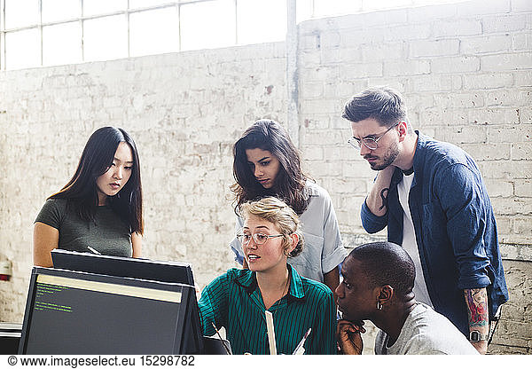 Young female entrepreneur having discussion over computer codes with hackers in office