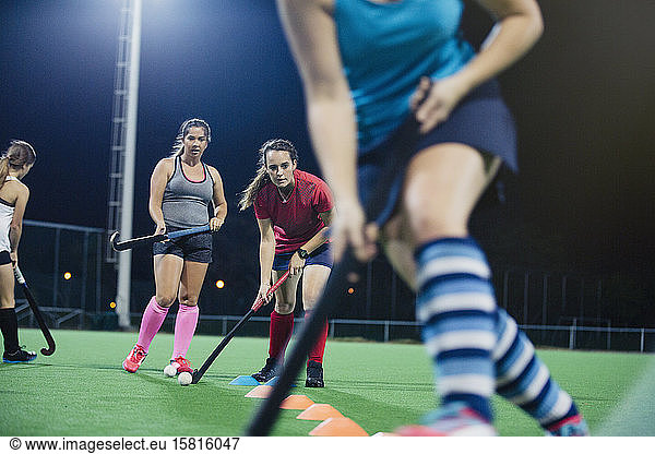 Young female field hockey players practicing sports drill on field