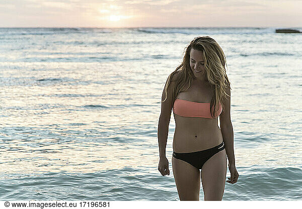 young female in bikini on beach at sunset