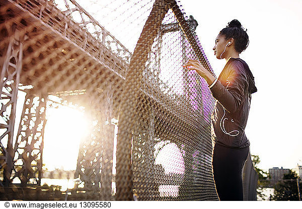 Young female jogger looking at Williamsburg Bridge on sunny day