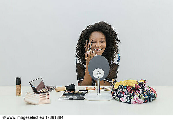 Young female make-up artist applying eyeshadow in studio