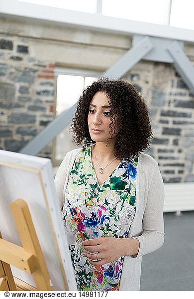 Young female painter painting canvas in studio