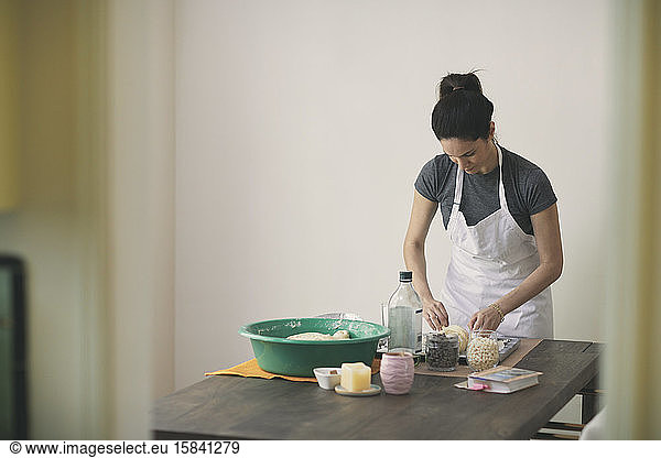 Young female preparing Challah bread on table while standing against wall at home