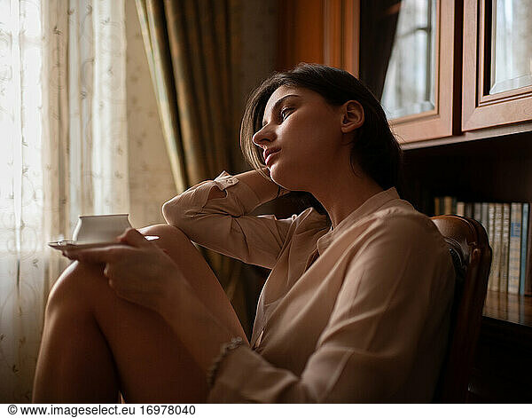 Young female resting with cup of hot beverage