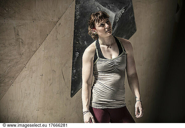 Young female rock climber standing in climbing gym
