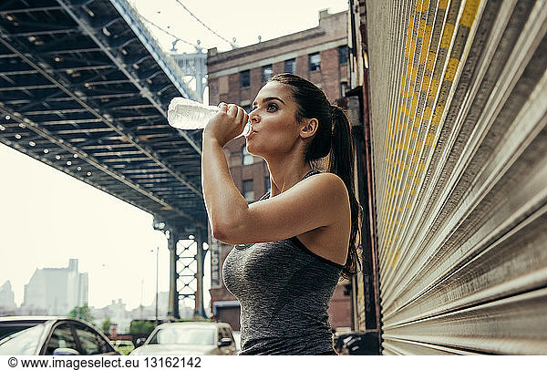 Young female runner drinking water  New York  USA