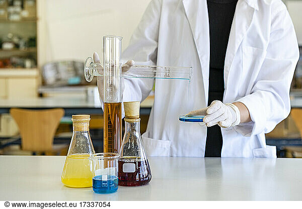 Young female scientist examining chemical on object plate at laboratory
