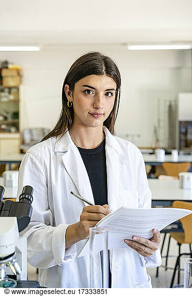 Young female scientist holding research document in laboratory