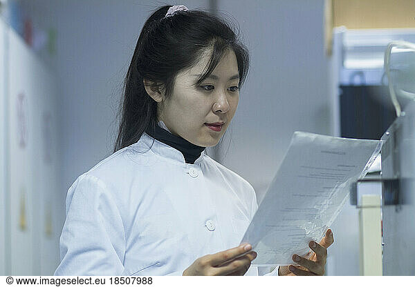 Young female scientist looking at report in a laboratory  Freiburg im Breisgau  Baden-Württemberg  Germany