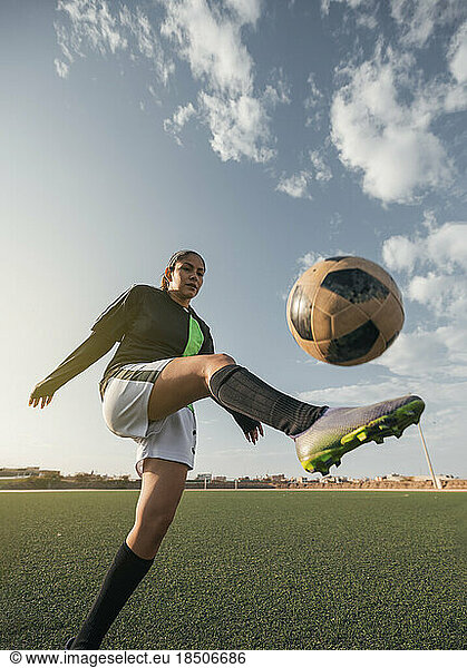 Young female soccer player kicking ball in a stadium. Selective focus.