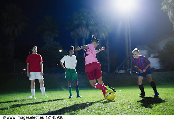 Young female soccer players practicing on field at night