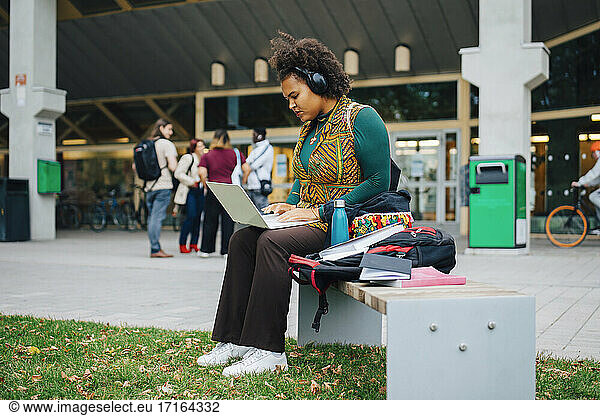 Young female student e-learning through laptop in campus