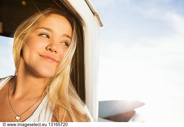 Young female surfer looking out of pickup truck window