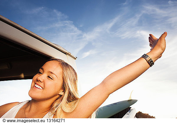 Young female surfer stretching next to pickup truck