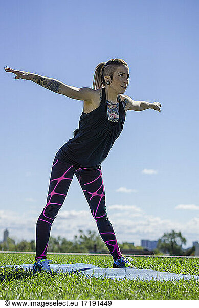 Young female with tattoos doing yoga and stretching