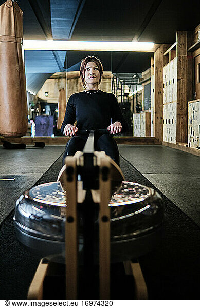 young fit woman using rowing machine at the gym