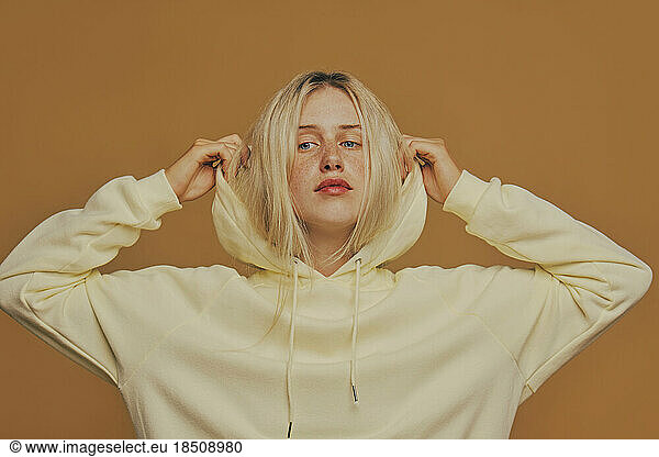 Young freckles woman wearing a yellow sweatshirt