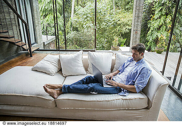 Young freelancer working on laptop in living room at home