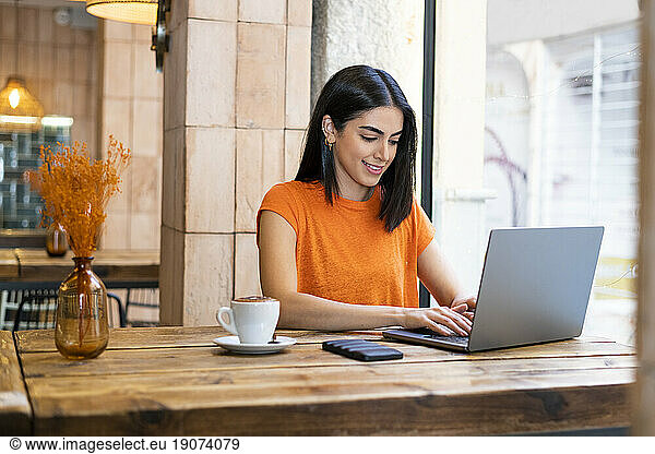Young freelancer working on laptop sitting in cafe
