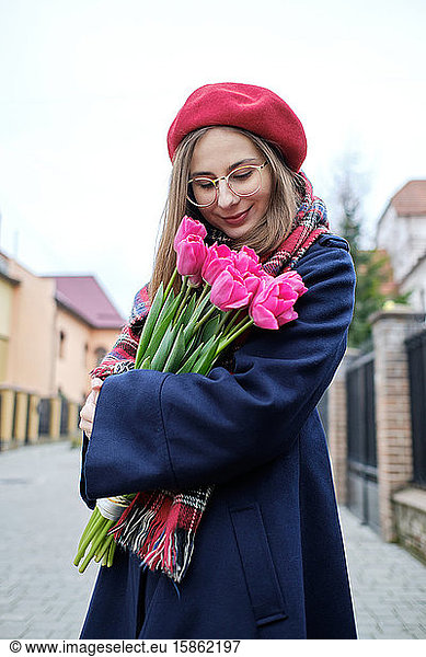 young french millennial girl in beret and coat with tulips in hands