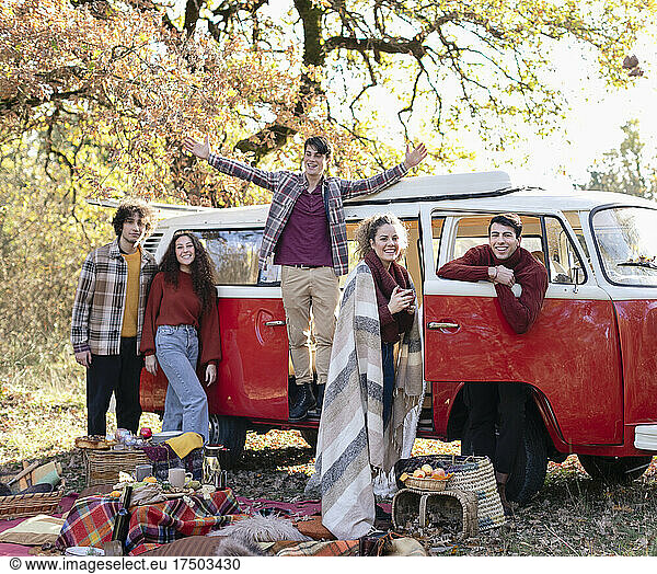 Young friends enjoying picnic on weekend in autumn forest