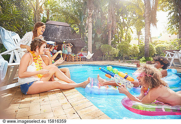 Young friends hanging out  playing with squirt gun at summer swimming pool