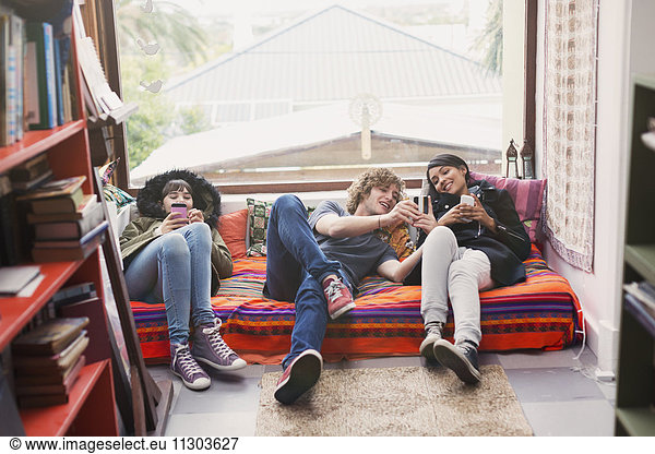 Young friends hanging out using cell phones in apartment window