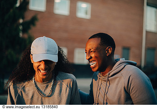 Young friends laughing while talking in city