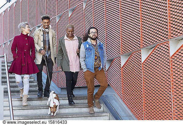 Young friends walking down down urban  modern stairs