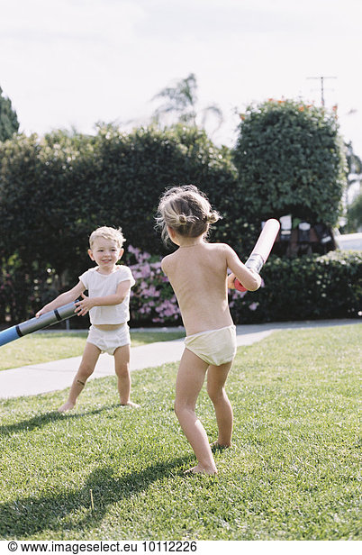 Young girl and young boy  two children wearing T-Shirt and shorts playing in a garden.