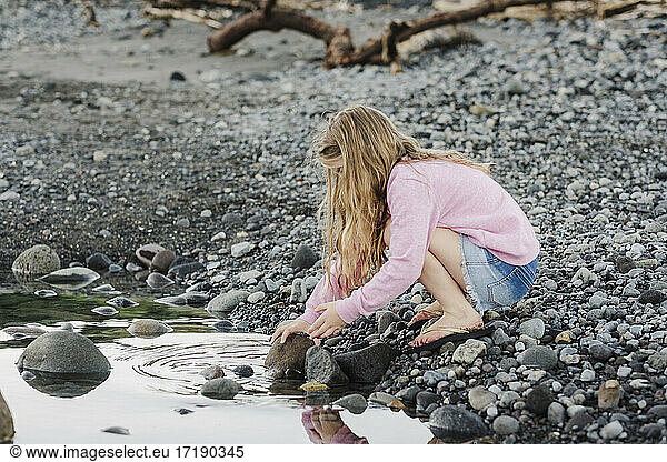 Young girl checking under rocks at the beach