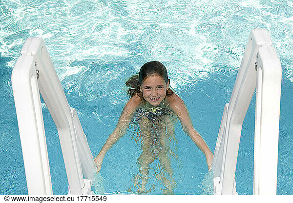 Young Girl Climbing A Swimming Pool Ladder; Ontario Canada