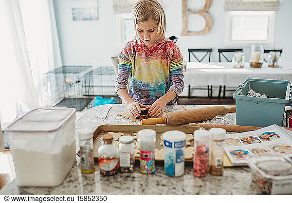 Young girl cutting out cookies in the kitchen