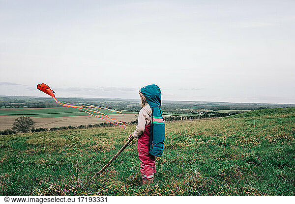 young girl flying a kite in the English countryside in winter