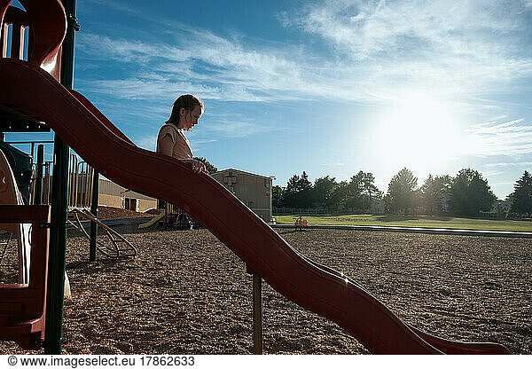 Young girl going down a slide on a playground