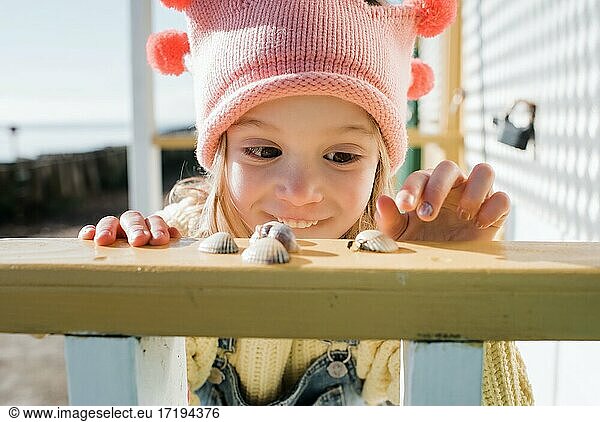 young girl happily choosing a shell from her collection at the beach