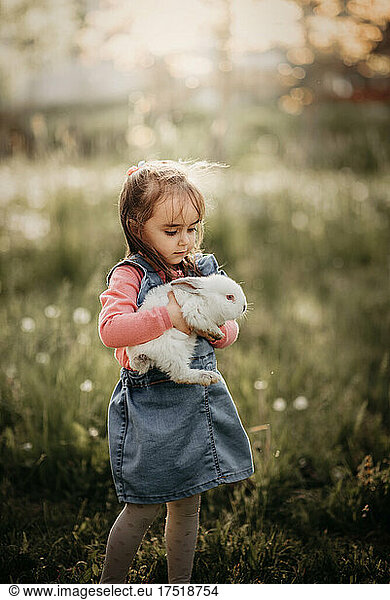 Young girl holding a rabbit with a blurry background.
