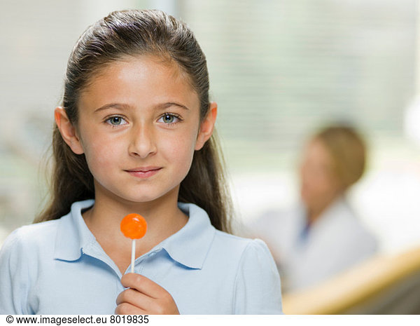 Young girl holding lollipop at the dentist's office portrait