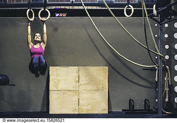 Young girl holding on rings at a crossfit gym