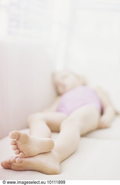 Young girl in a pink swimsuit lying on a sofa  taking a nap.