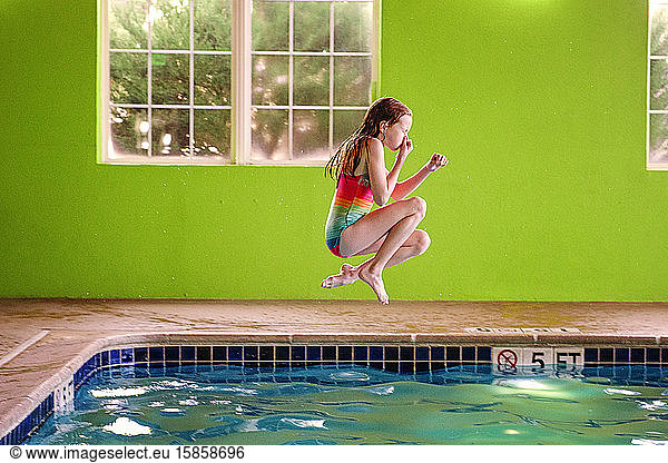 Young Girl Jumping into an Indoor Swimming Pool
