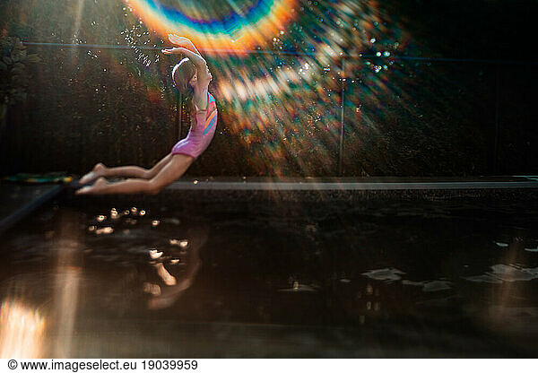 young girl jumping on the pool on a sunny day