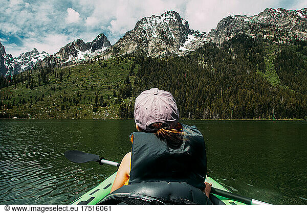 Young girl kayaking in lake near snowy mountain