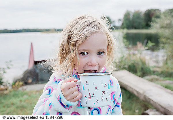 young girl laughing drinking hot chocolate whilst camping outdoors